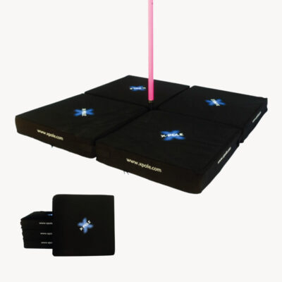 A black x pole, pole dancing crash mat set up on a pink pole dancing pole